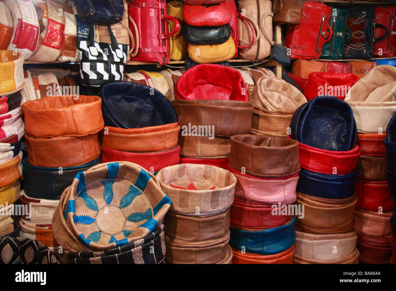 Traditional Moroccan leather pouffes/soft seats & bags for sale in  a tannery shop deep in the depths of Fes/Fez medina, Morocco Stock Photo