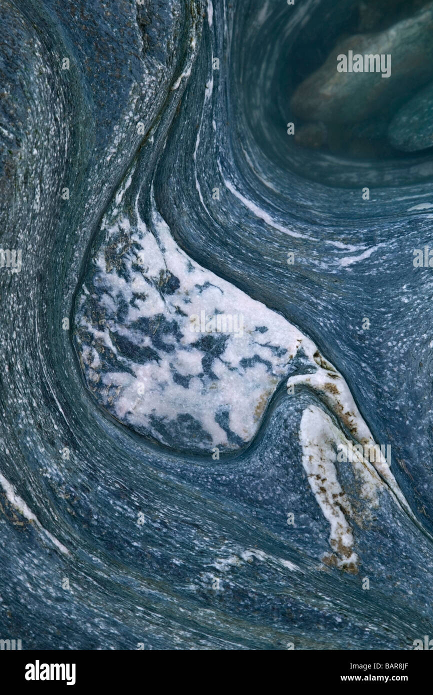 Study of an 'S-shaped' and curvy granite rock with a small pool of sea water in the top right corner. Stock Photo