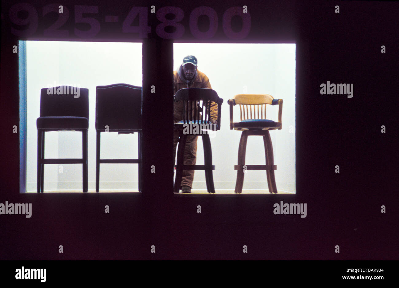 Worker setting up chairs in window display Stock Photo - Alamy