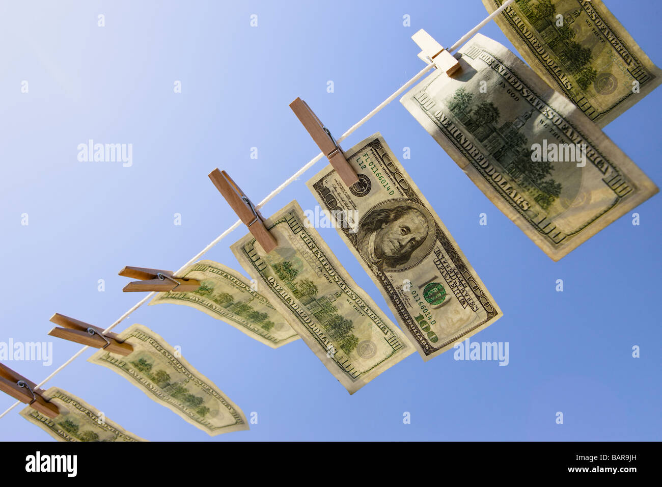 Money Laundering - Dollars: $100 dollar bills drying in the wind under a deep blue sky. Stock Photo
