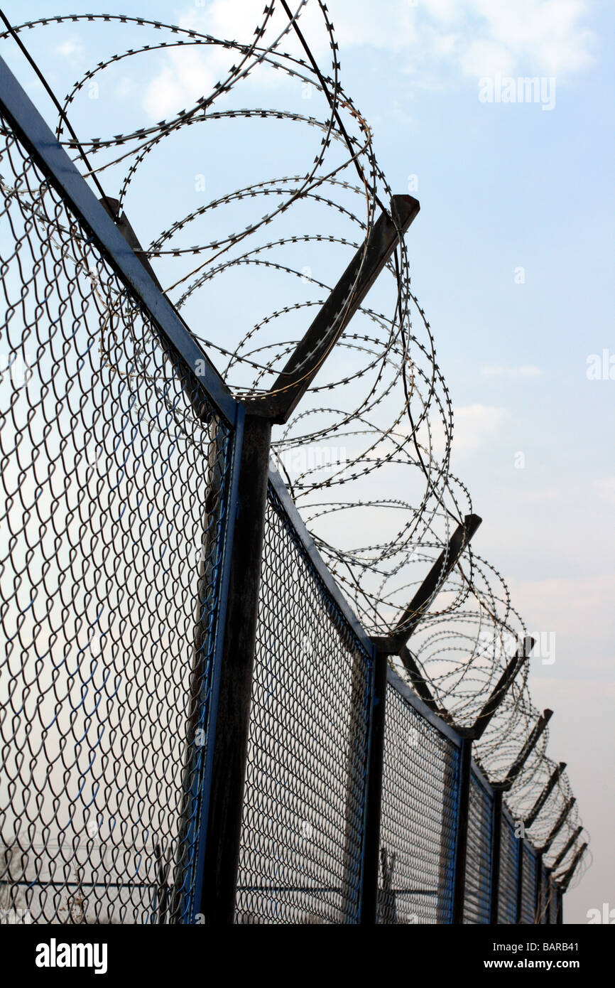 fence with barbed wire under blue sky Stock Photo - Alamy