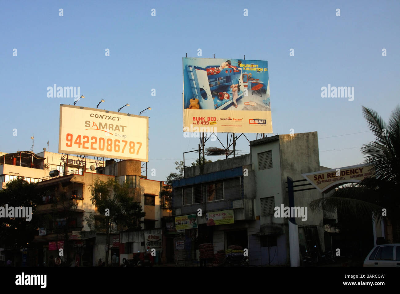 billboards in the sunset against a blue sky with dirty buildings and street view below in Pune, India Stock Photo