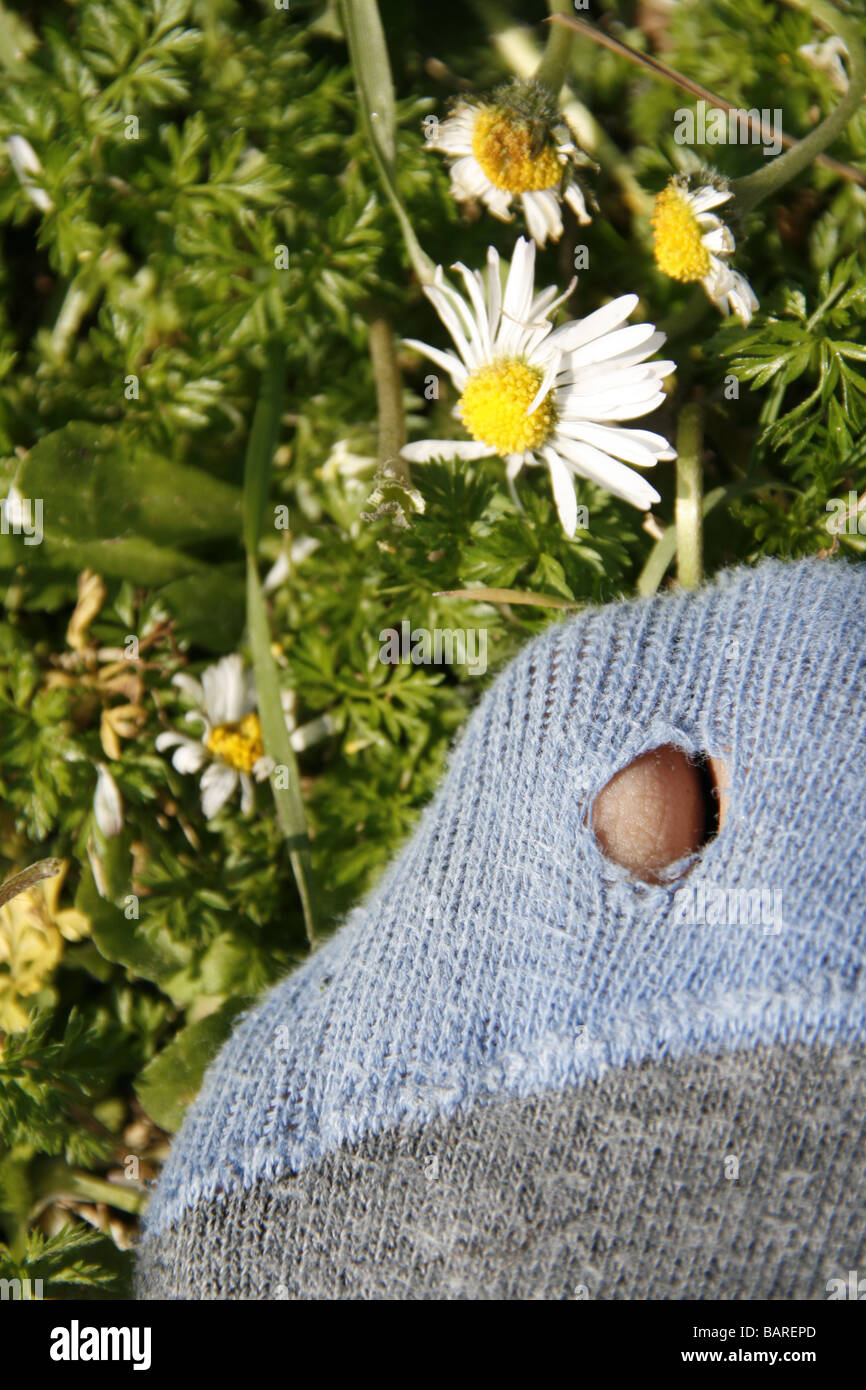 person with hole in sock standing in field Stock Photo