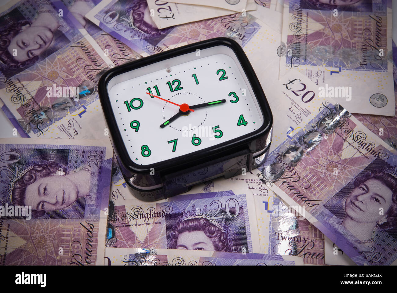 Alarm clock over a pile of British money Stock Photo