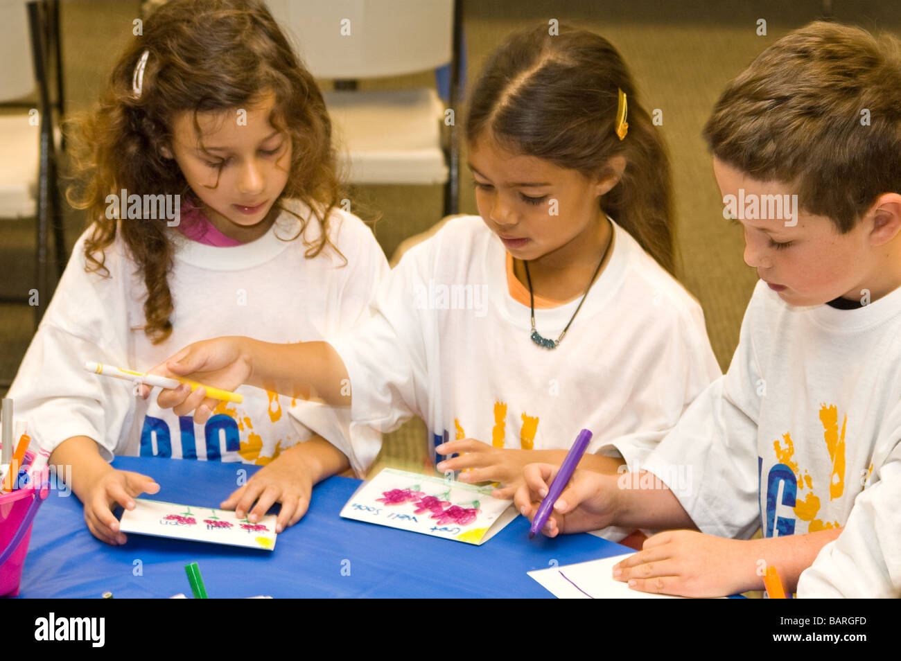 Three young children colors cards to be donated to the city of Irvine's