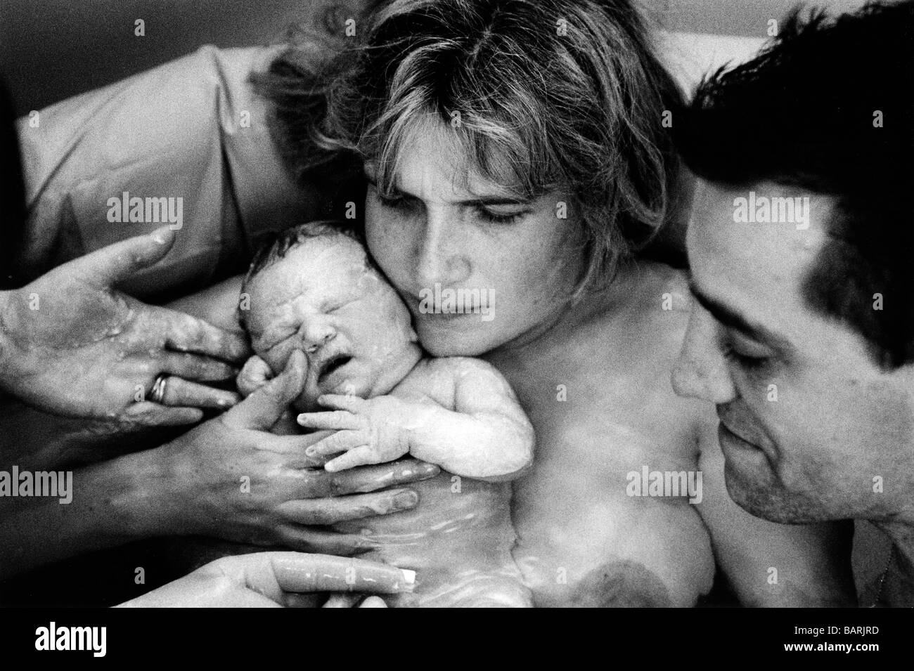 Gail's baby taking her first breaths immediately after delivery in the birth pool with her husband Peter, Edgware Birth Centre. Stock Photo
