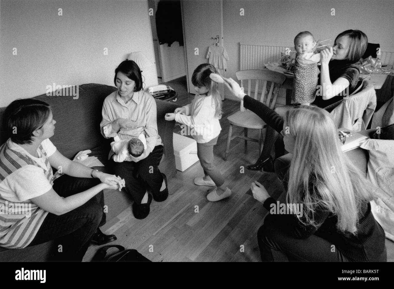 Community midwife  (left) visits a mother who is concerned that her child born the day before has not fed since birth. Stock Photo