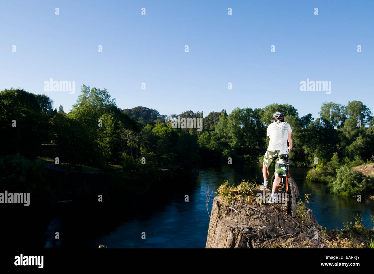 man standing next to mountain bike looking at view over Waikato river,  Cambridge, New Zealand Stock Photo