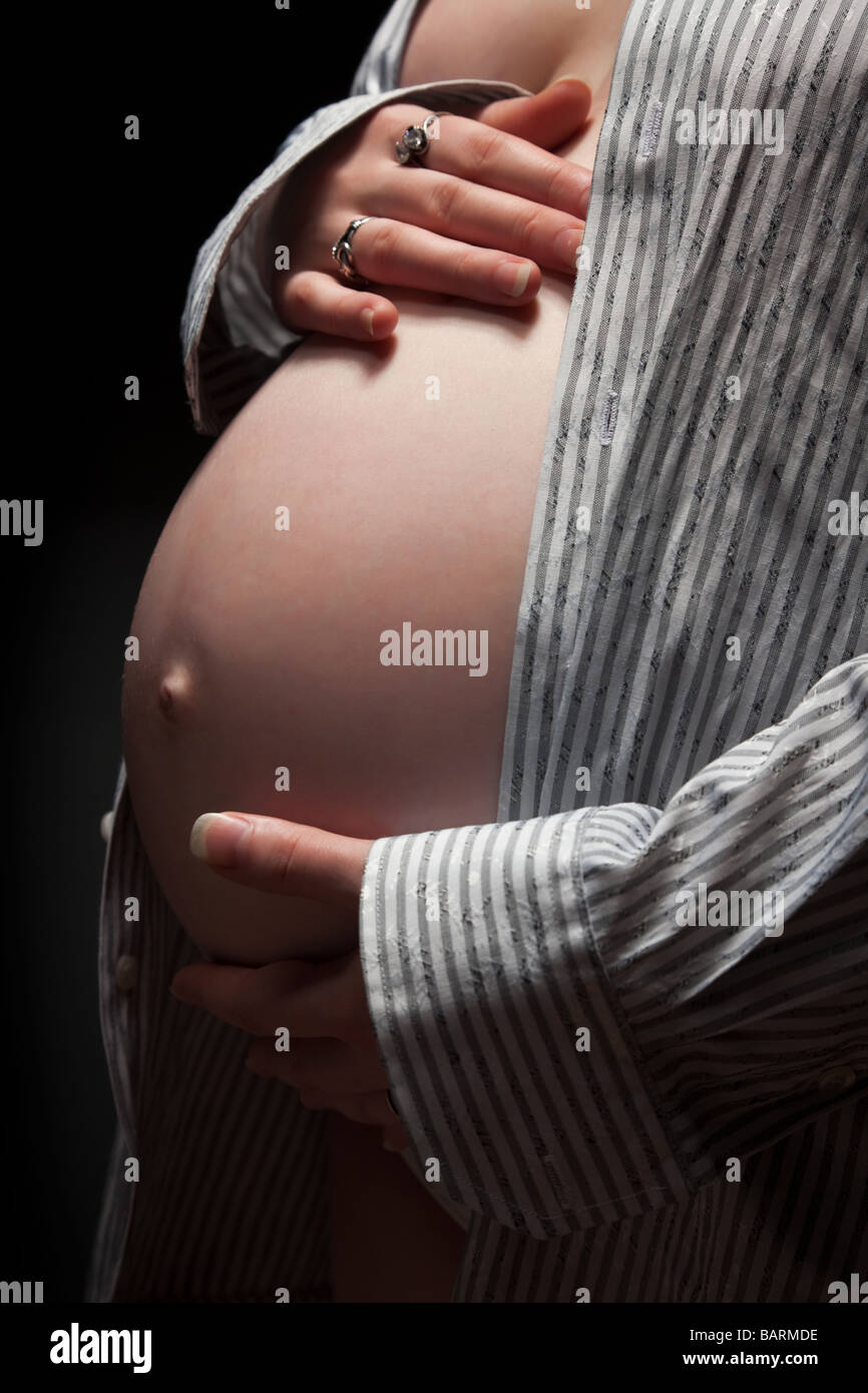 pregnant woman holding her belly over black background Stock Photo