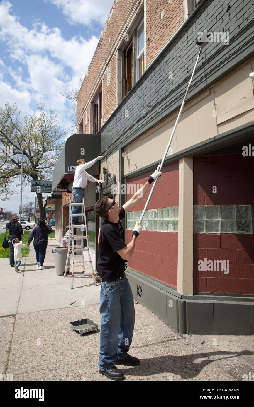 Volunteers paint building as part of community cleanup Stock Photo