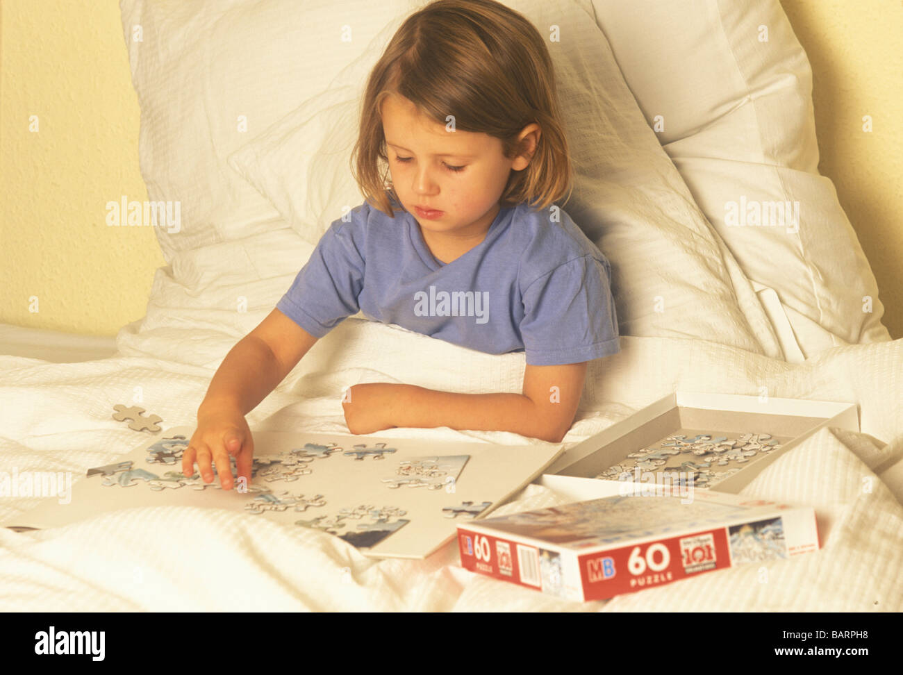child doing a jigsaw puzzle sitting up in bed convalescing Stock Photo