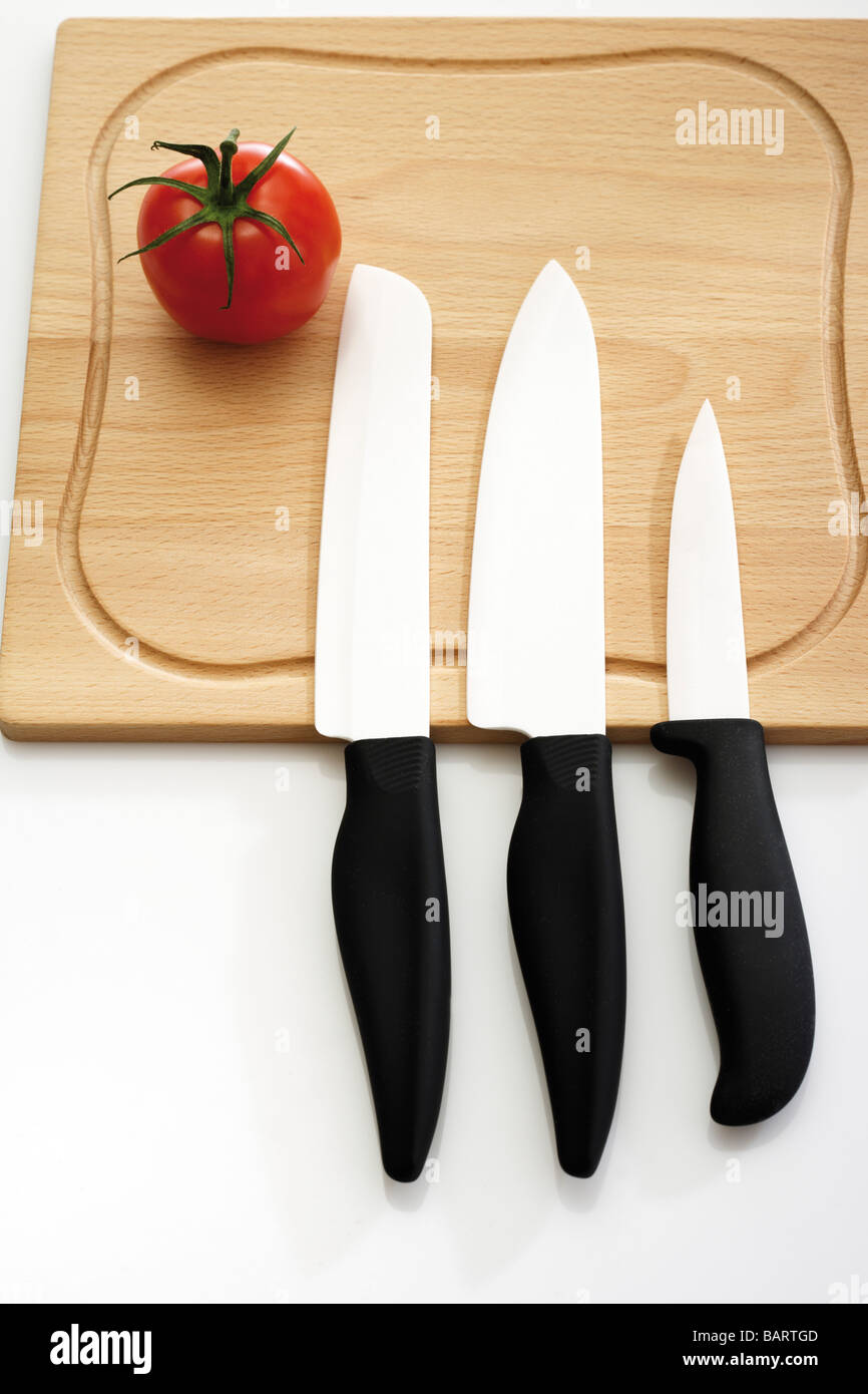 Tomato and knives on chopping board, elevated view Stock Photo