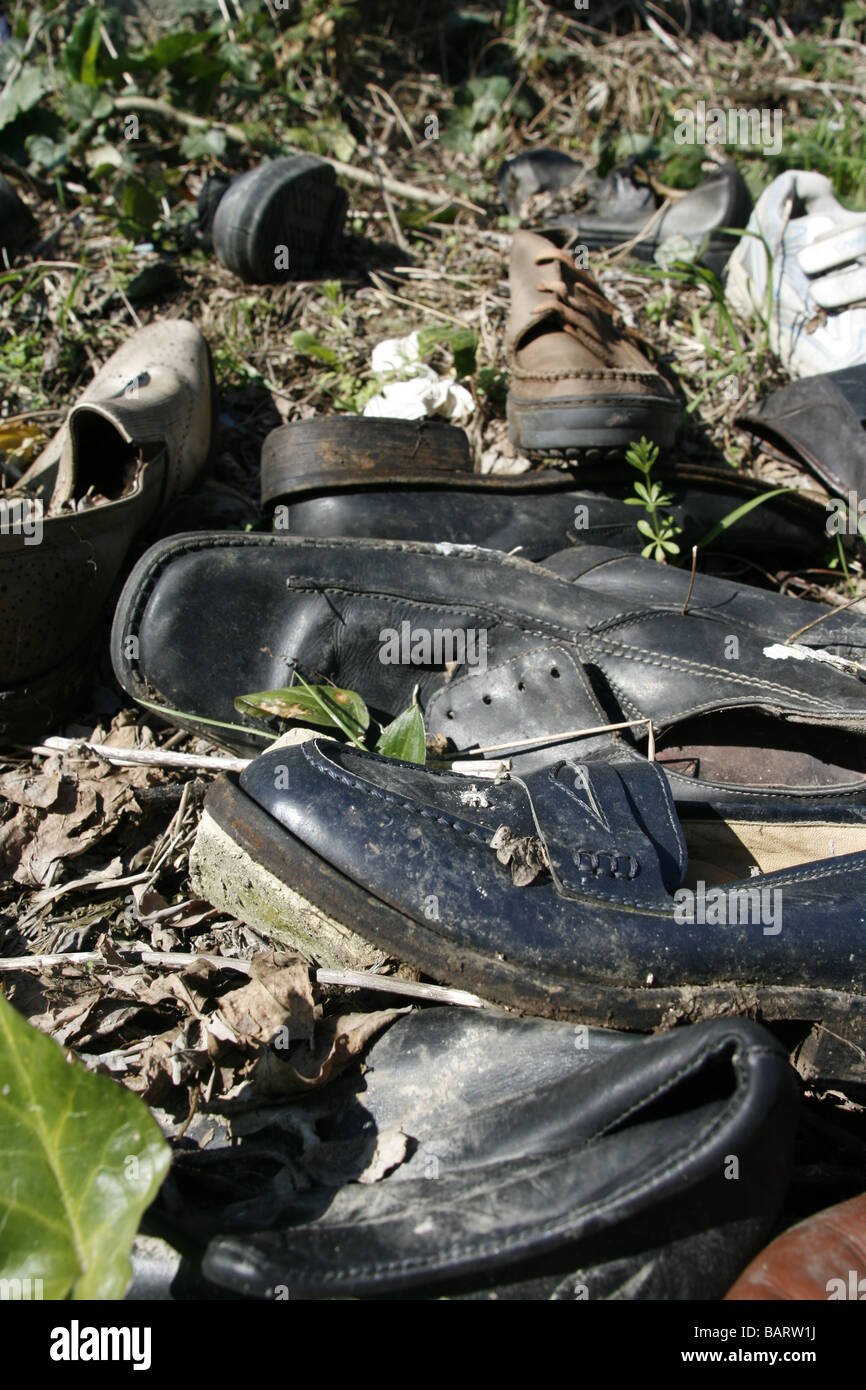 lots of pairs of shoes left in field in countryside Stock Photo