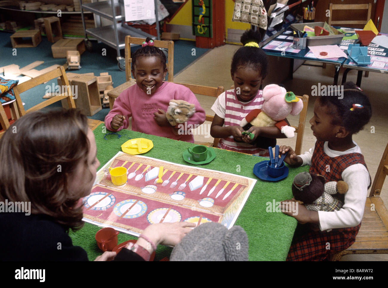 Nursery school children playing with table settings identifying objects ...