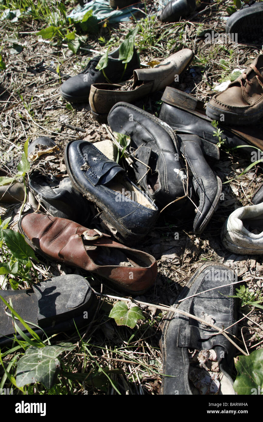 lots of pairs of shoes left in field in countryside Stock Photo