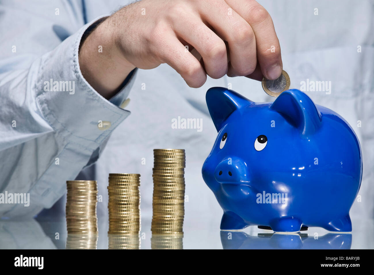 Person putting Euro coin into piggy bank Stock Photo - Alamy