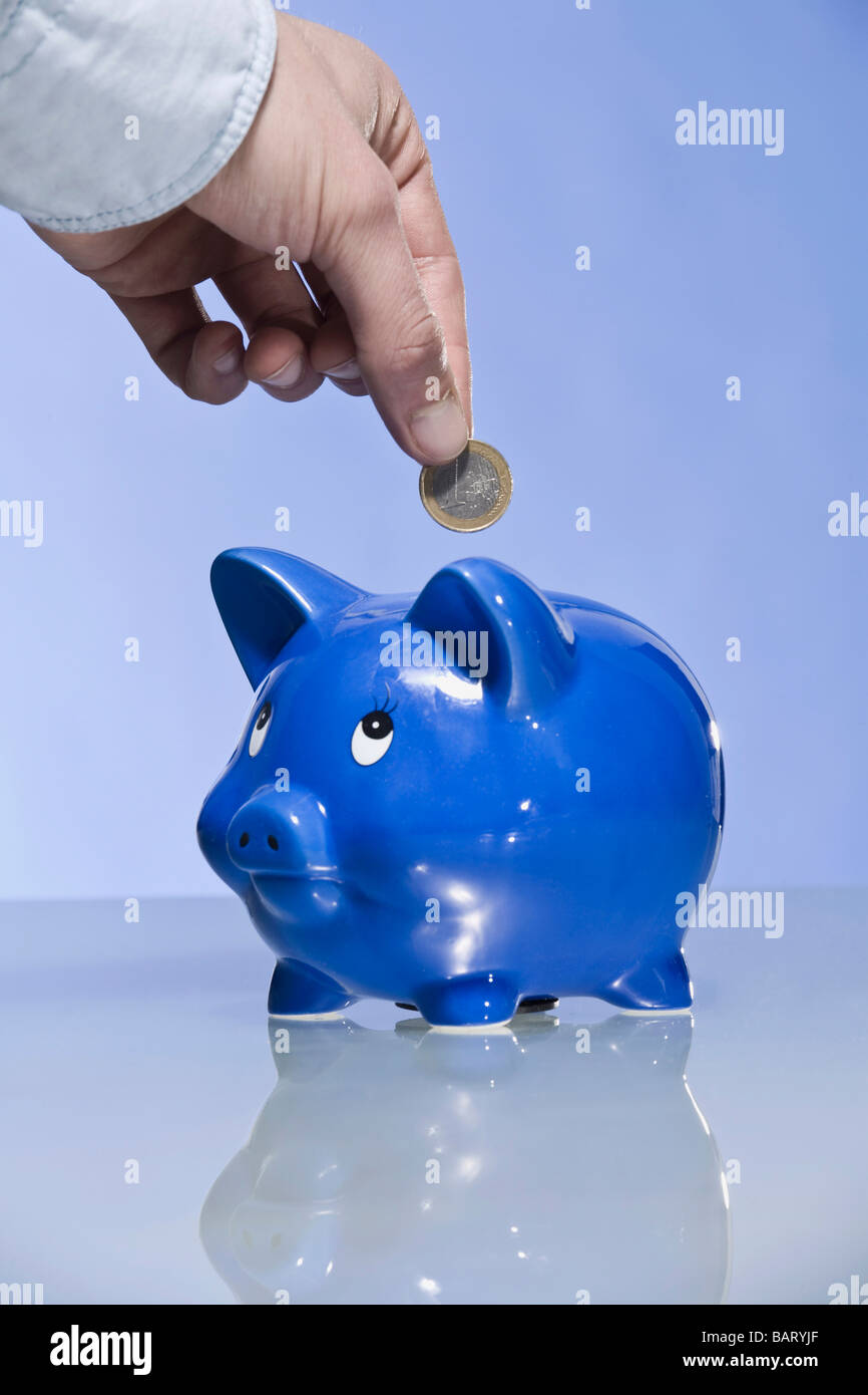 Person putting Euro coin into piggy bank Stock Photo - Alamy