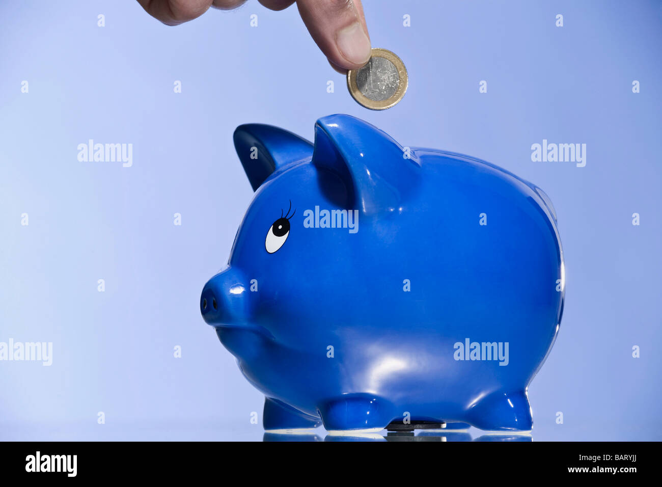 Person putting Euro coin into piggy bank Stock Photo - Alamy