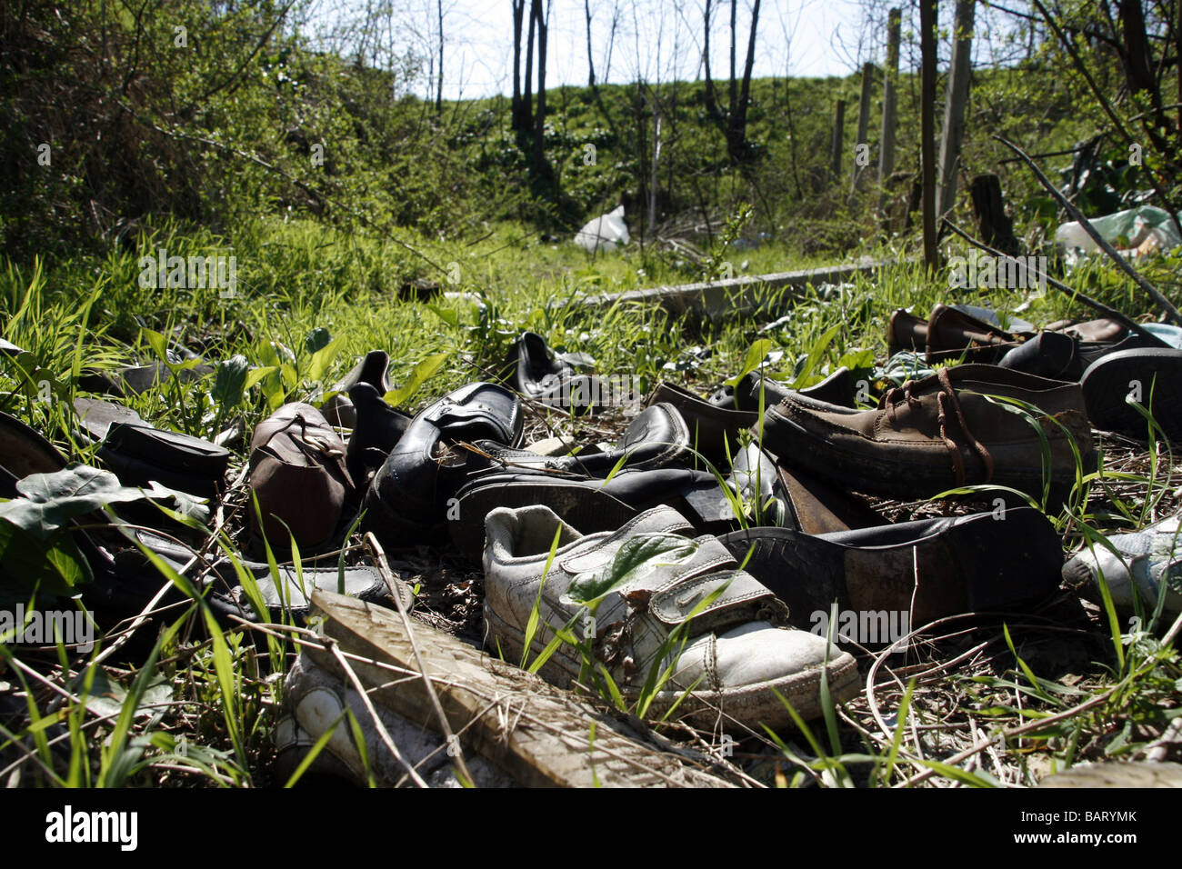 lots of pairs of shoes left in field in countryside Stock Photo