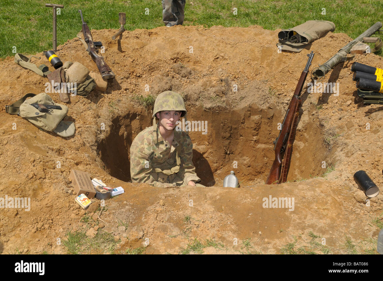 man dressed as a American soldier sits in a foxhole in a reenactment of