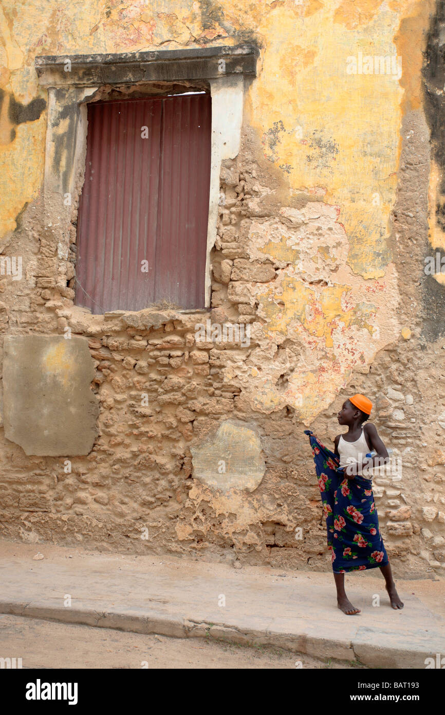 Young African girl on Ilha Mozambique looking at an old windowframe Stock Photo