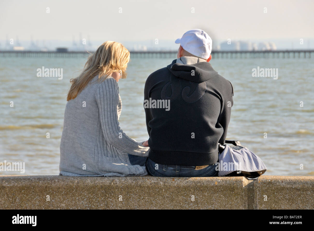Couple sitting on seawall Southend on Sea Essex England UK Stock Photo