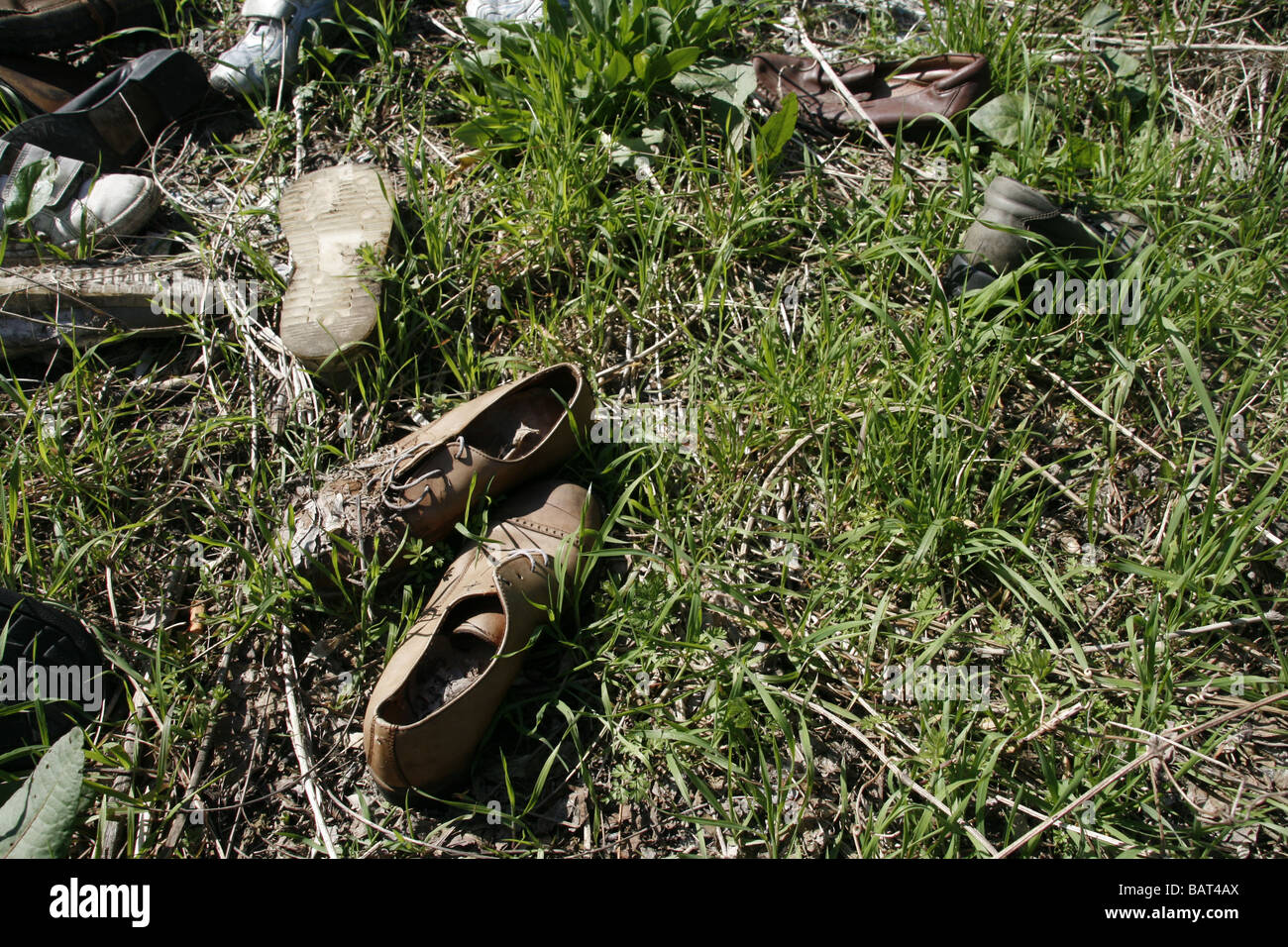 lots of pairs of shoes left in field in countryside Stock Photo