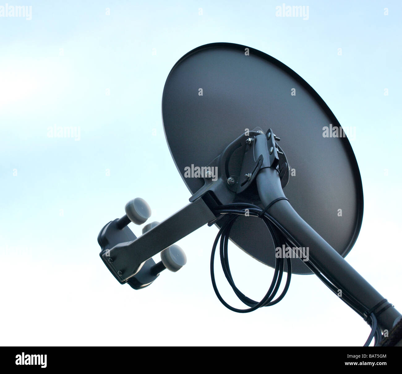 satellite television tv receiver dish in gray against a light blue sky showing arm dish cables Stock Photo