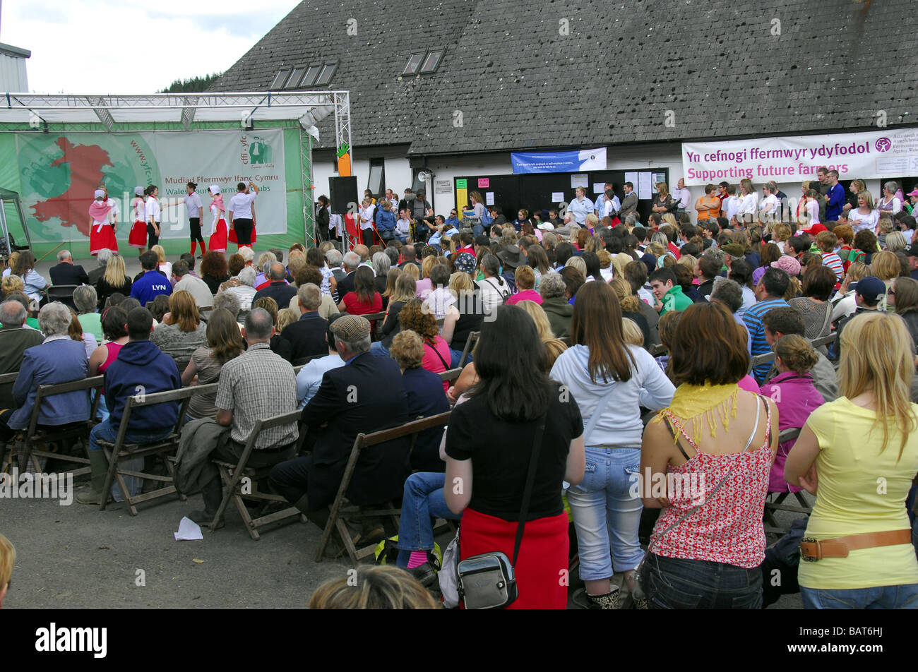 Audience watching outdoor performance of traditional Welsh country dancing at the Young Farmers stage area at Royal Welsh Show. Stock Photo