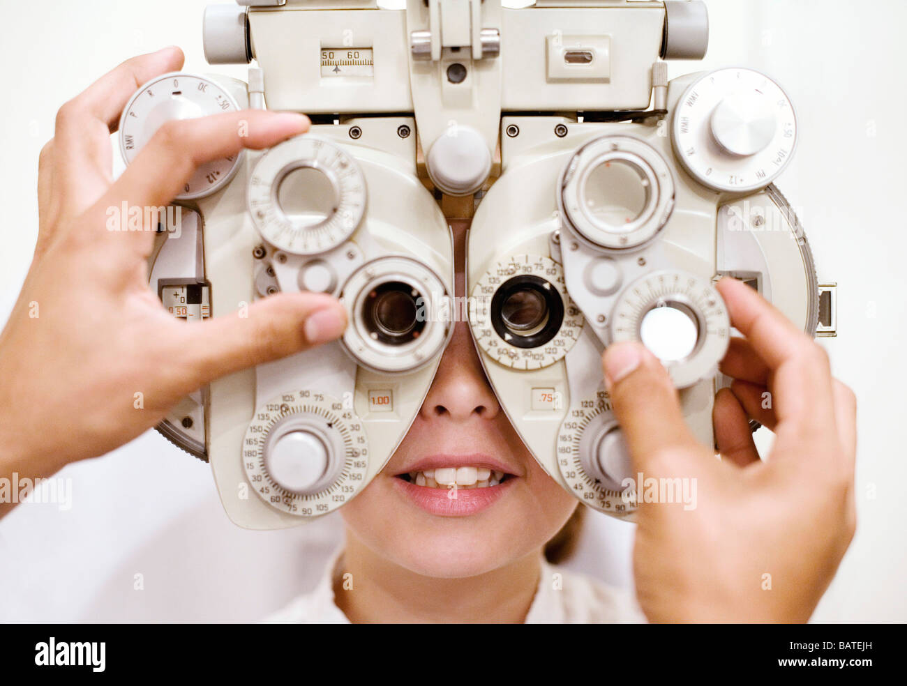 Eye examination. Optician using a phoropter to examine a ten year old