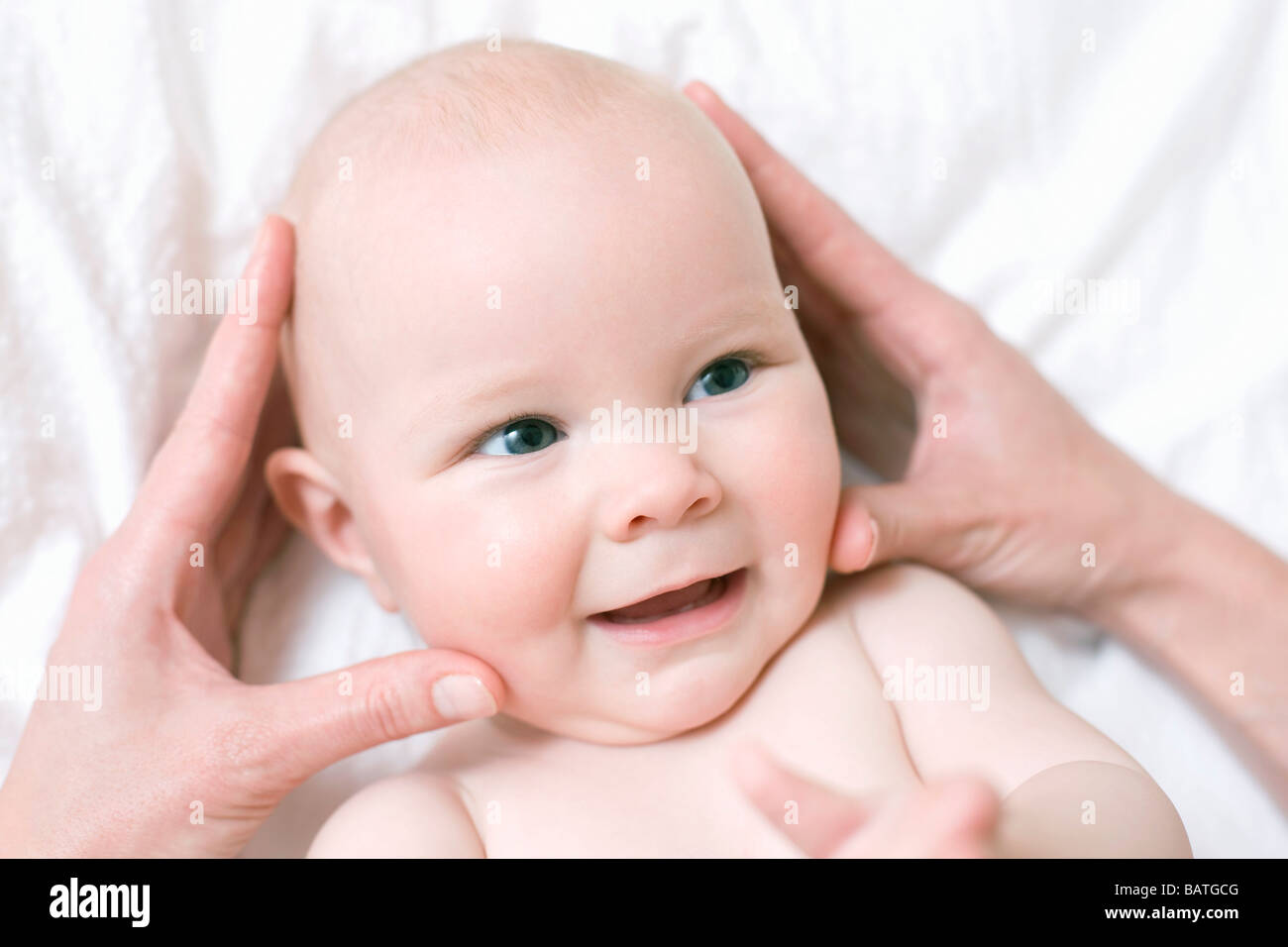 Baby massage. Hands massaging the head of a 7 month old baby girl Stock