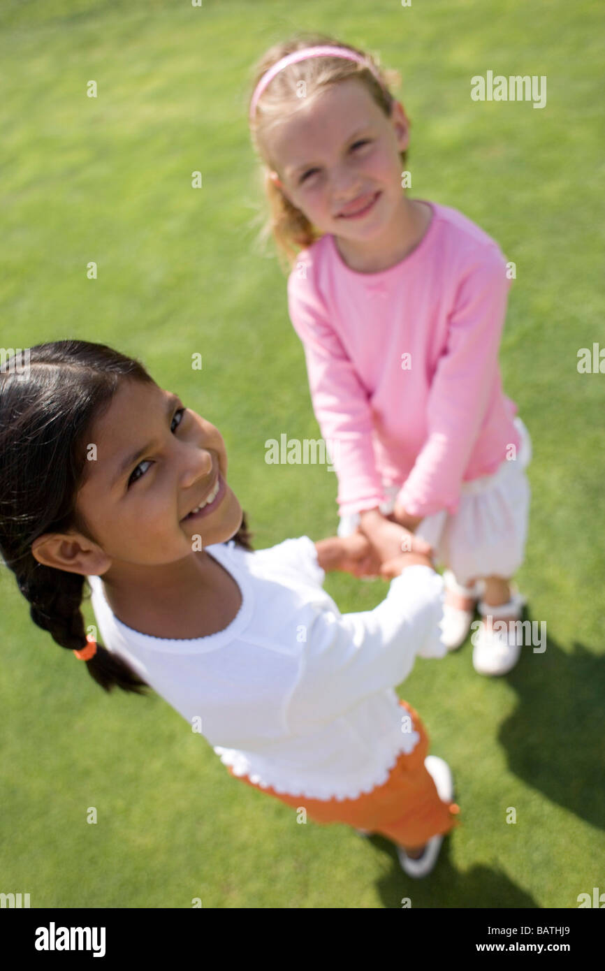 Happy girls holding handswhile playing on grass Stock Photo - Alamy