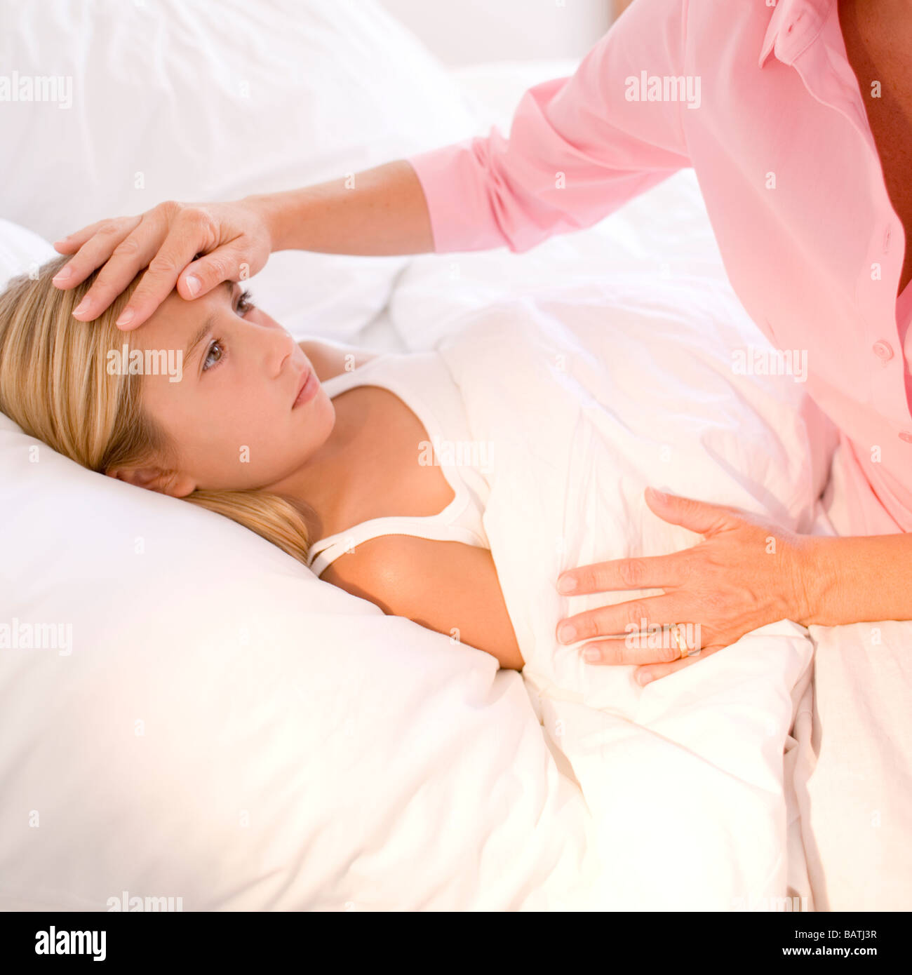 Ill child. Mother checking her daughter's temperature with her hand. Stock Photo
