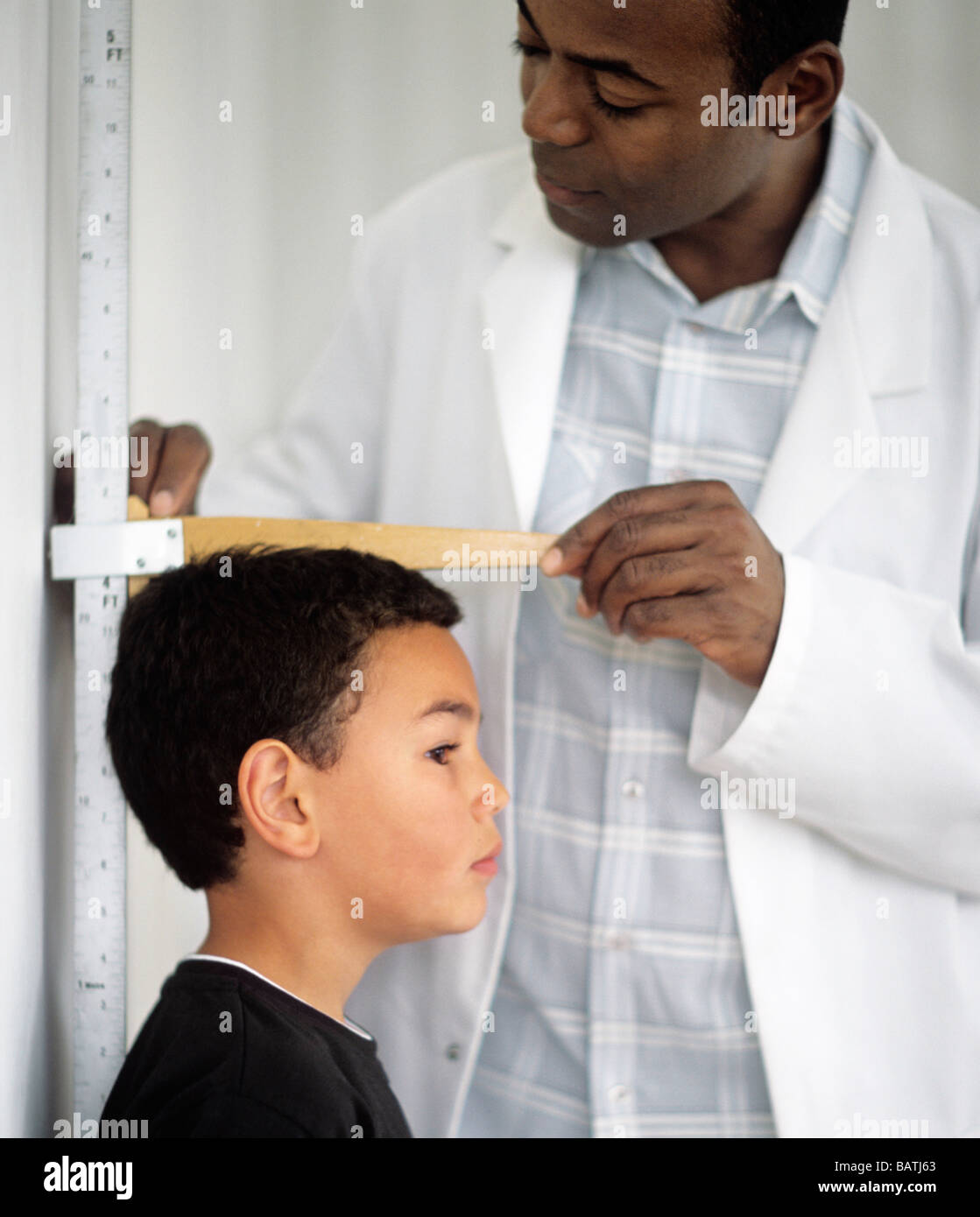 Height measurement. 7 year old boy having his height measured by a doctor. Stock Photo