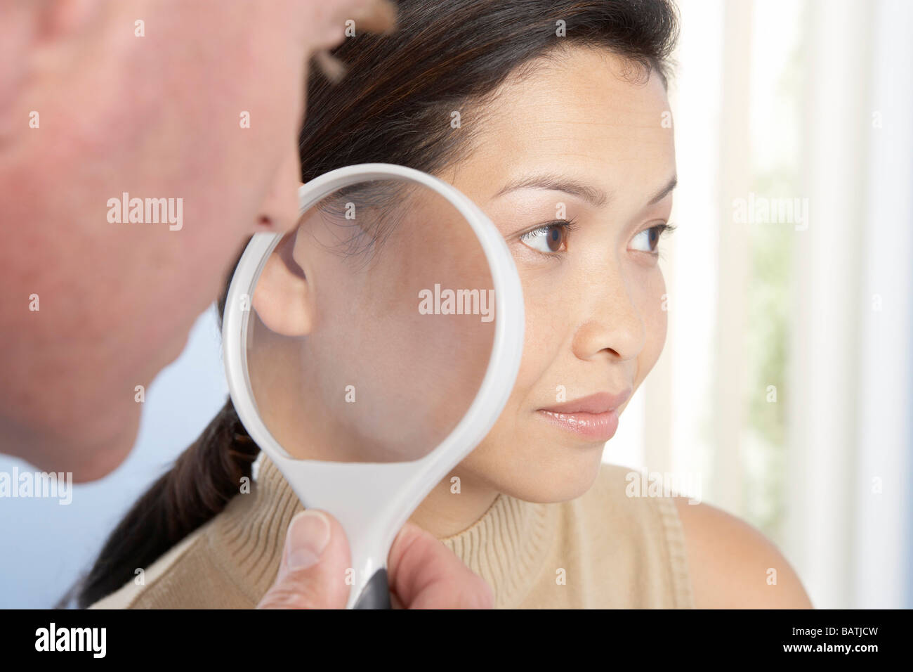 Dermatological examination. Dermatologist using a magnifying glass to