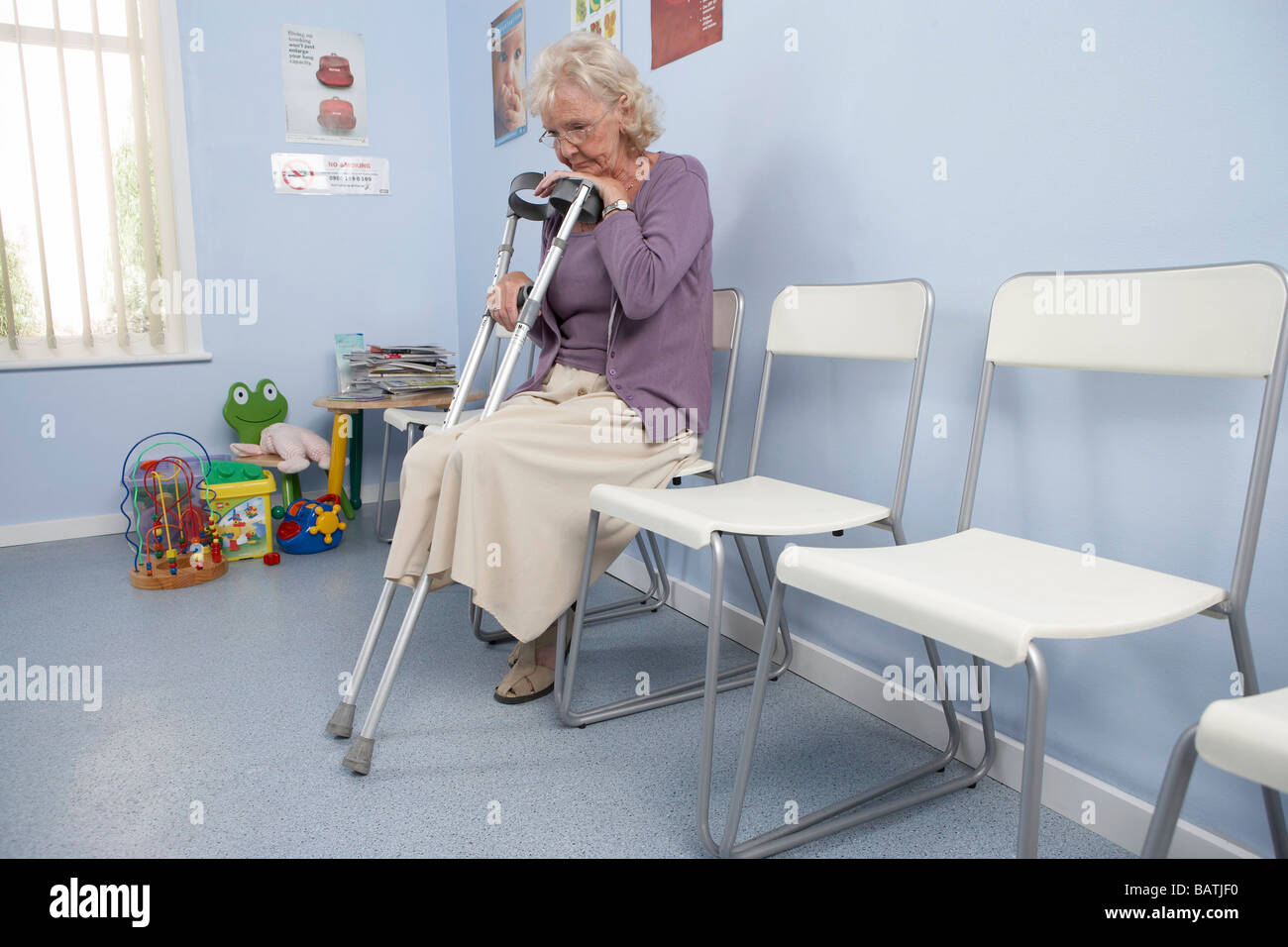 Elderly patient leaning on her crutches in a general practice waiting