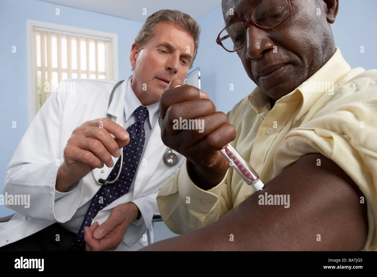 Injecting insulin. General practitioner instructing his patient to use ...