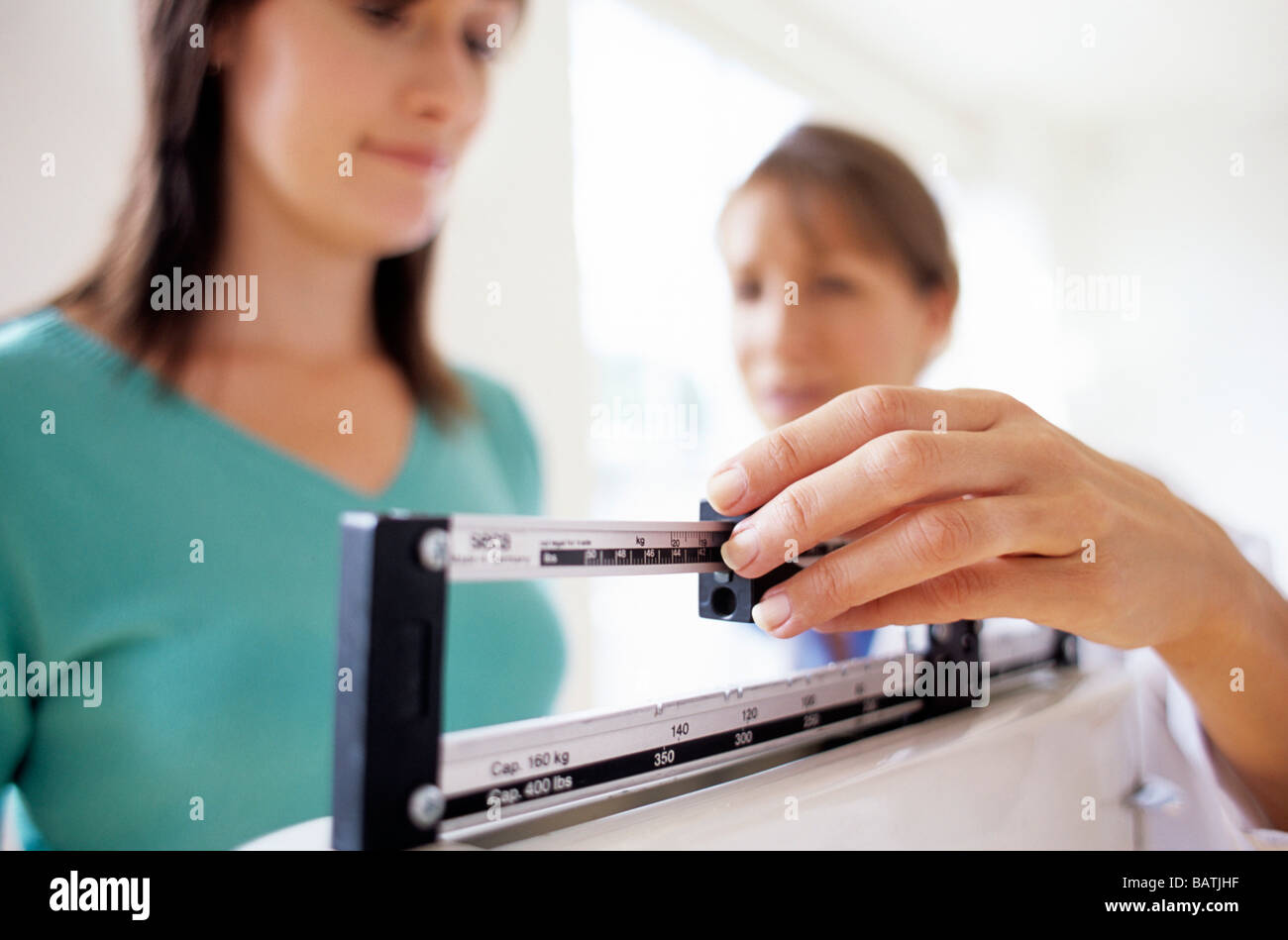 Weight checkup. General practice doctor adjusting the balance on