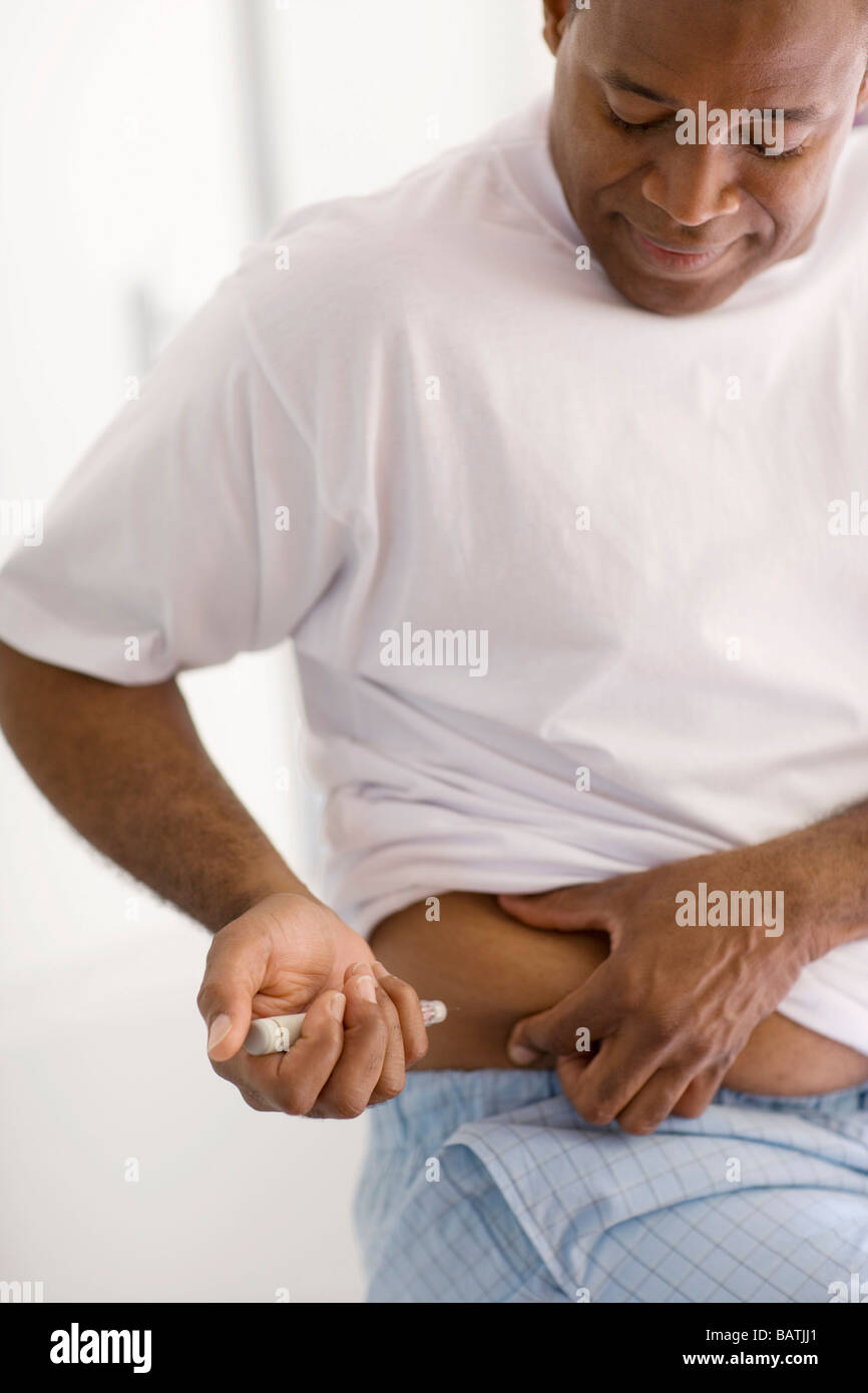 Insulin injection. Diabetic man injecting himself with insulin. He is