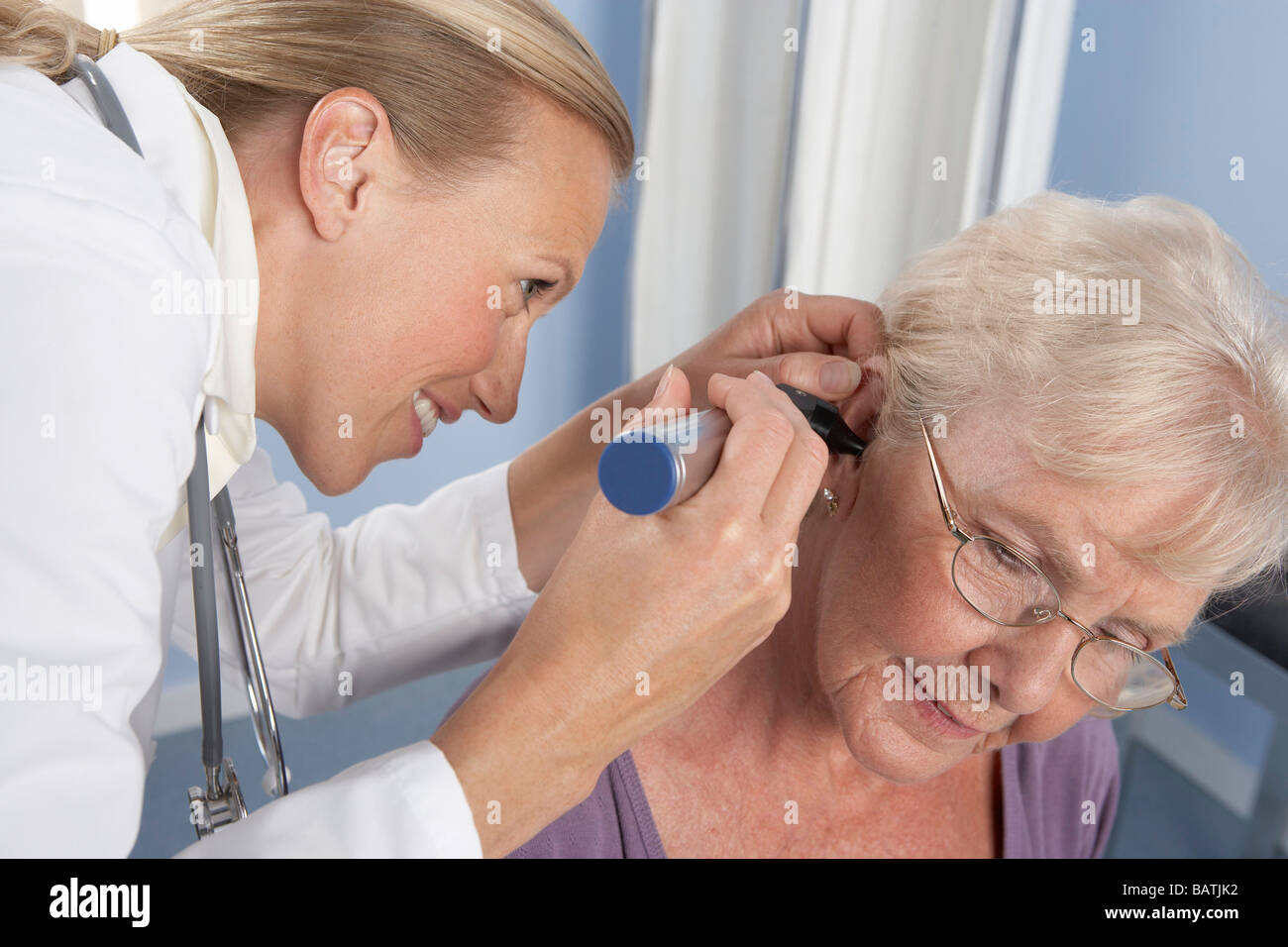 Ear examination. General practitioner using an otoscope to examine