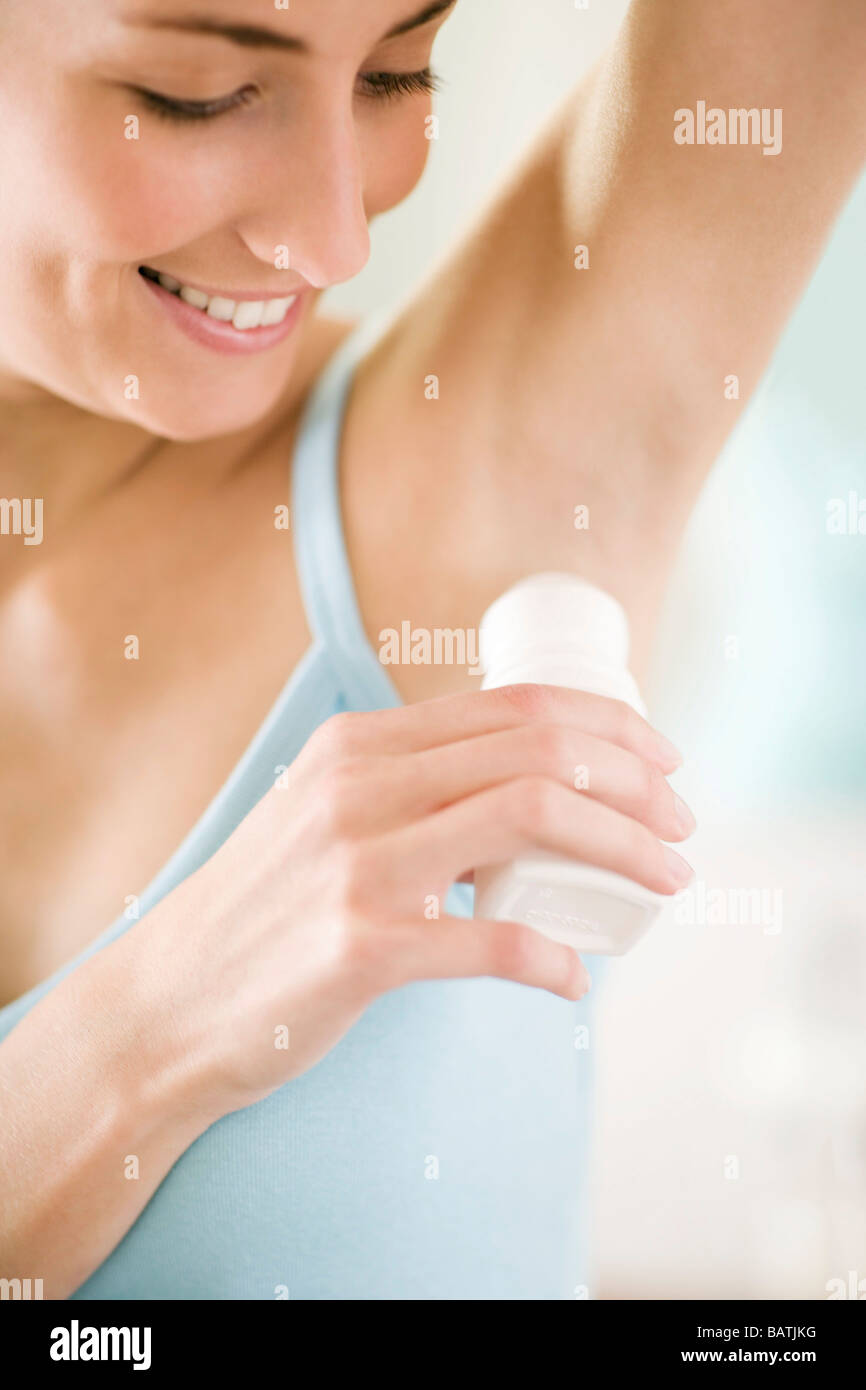Woman applying deodrant to her underarm area. Stock Photo