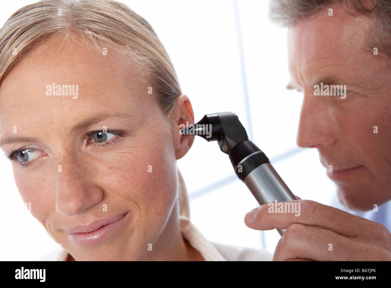 Ear examination. General practice doctor using an otoscope to examine a