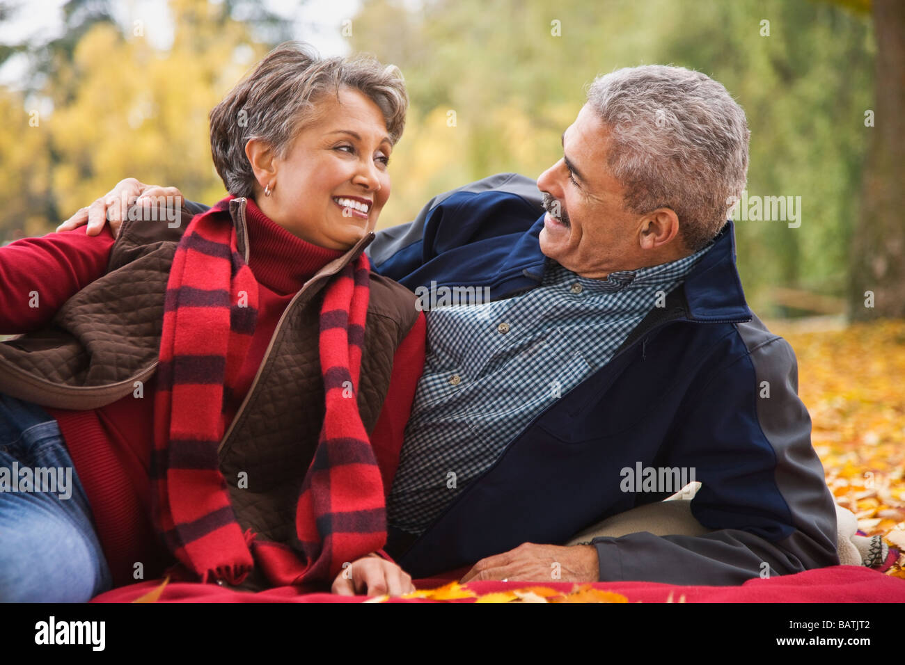 African couple laying on blanket among autumn leaves Stock Photo