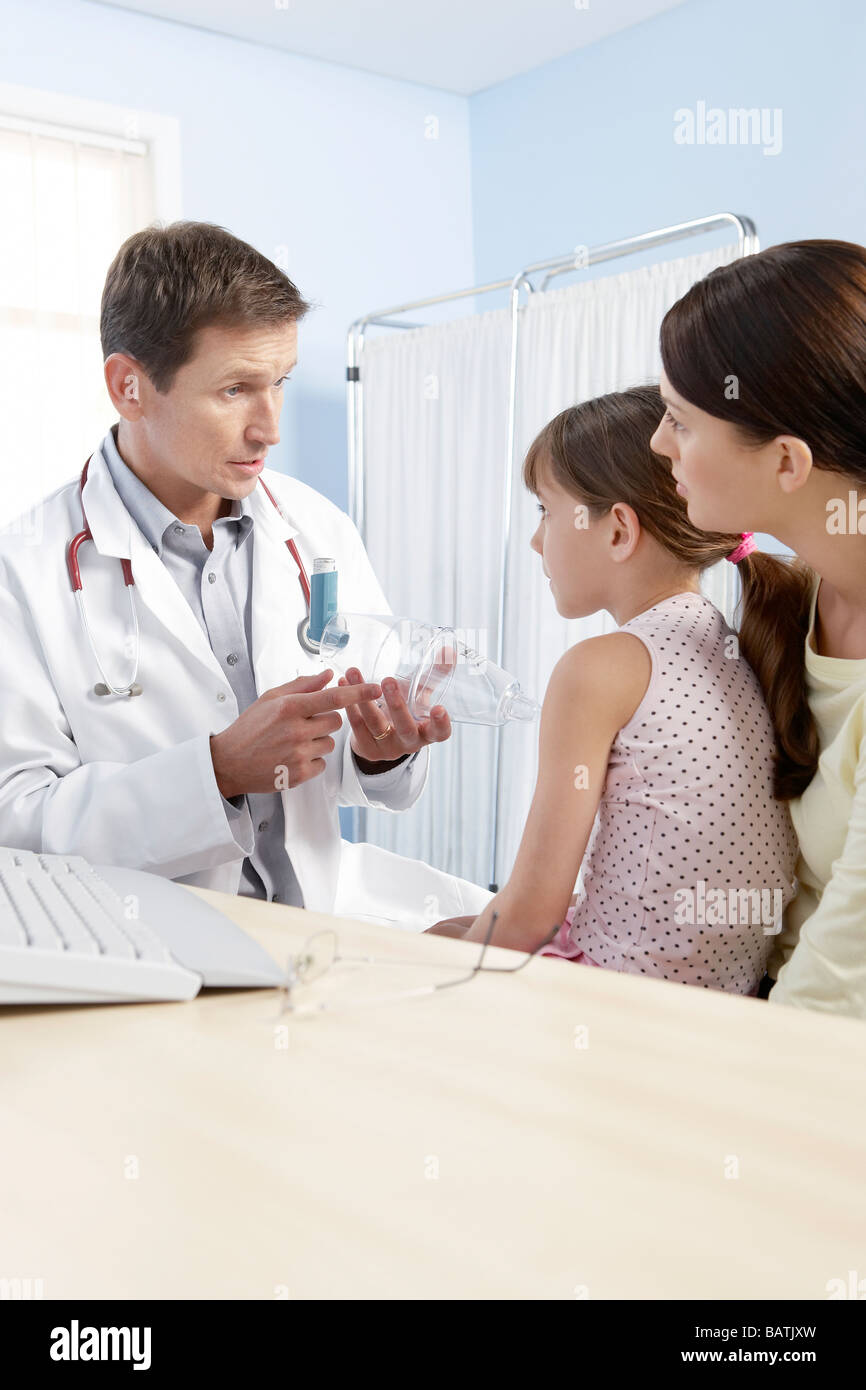 Asthma spacer. GP helping a young girl to use a spacer (plastic chamber