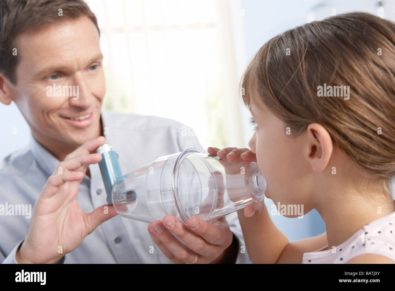 Asthma spacer. GP helping a young girl to use a spacer (plastic chamber