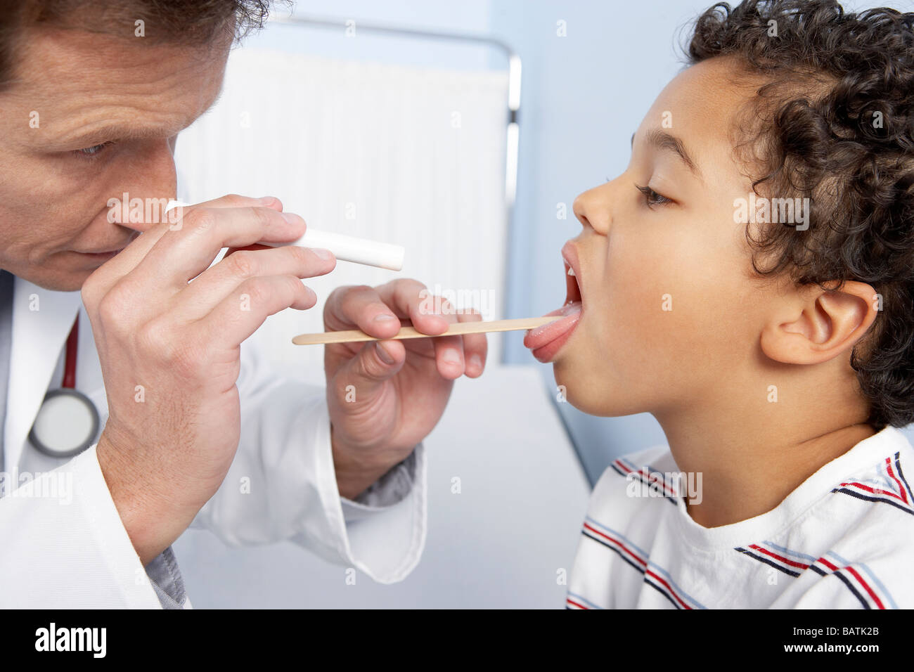 Paediatric examination. Doctor using a tongue depressor to allow an