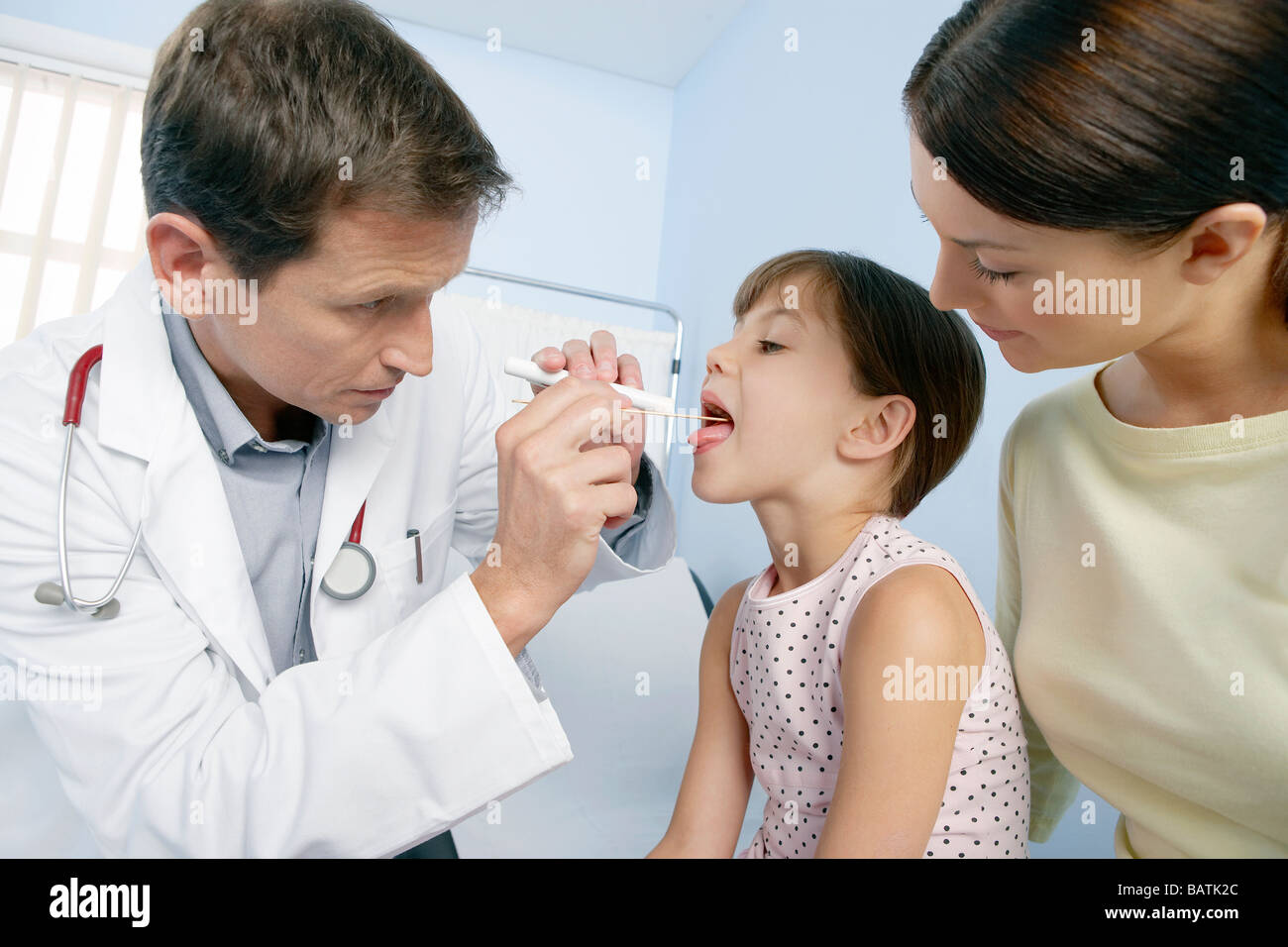Paediatric examination. Doctor using a tongue depressor to allow an