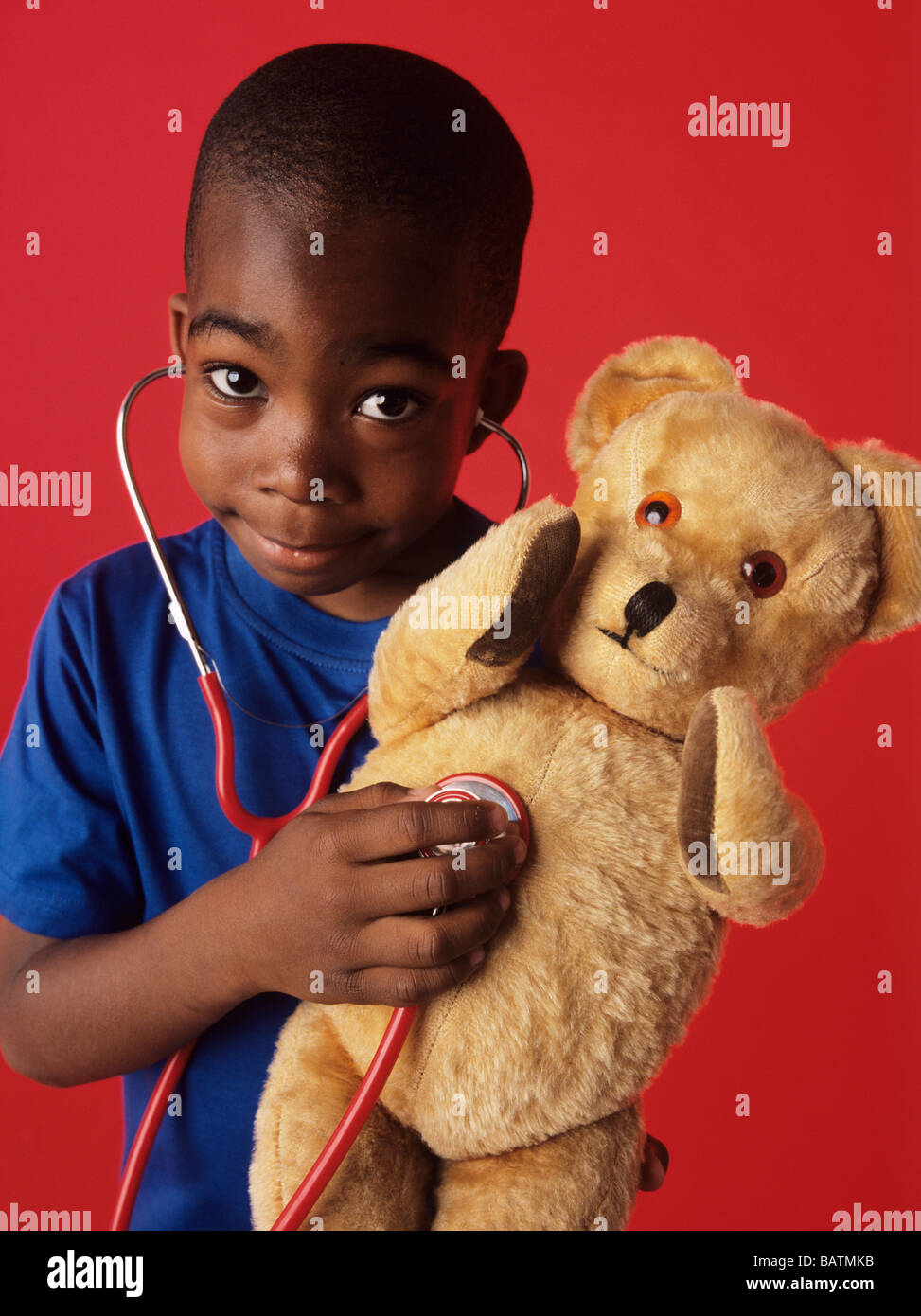 Pretend examination. 6-year-old boy listening to his teddy bear's heartbeat using a stethoscope. Stock Photo