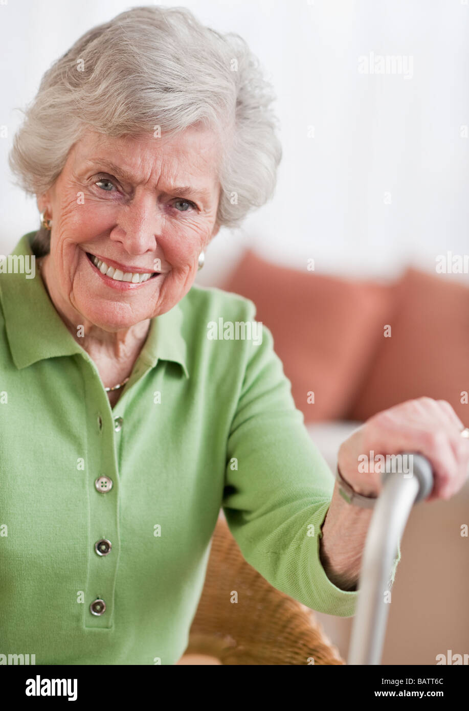 Senior woman sitting and holding walking stick Stock Photo - Alamy