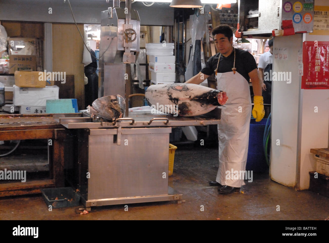 Worker in the Tsukiji fish market Tokyo Japan cuts frozen tuna fish